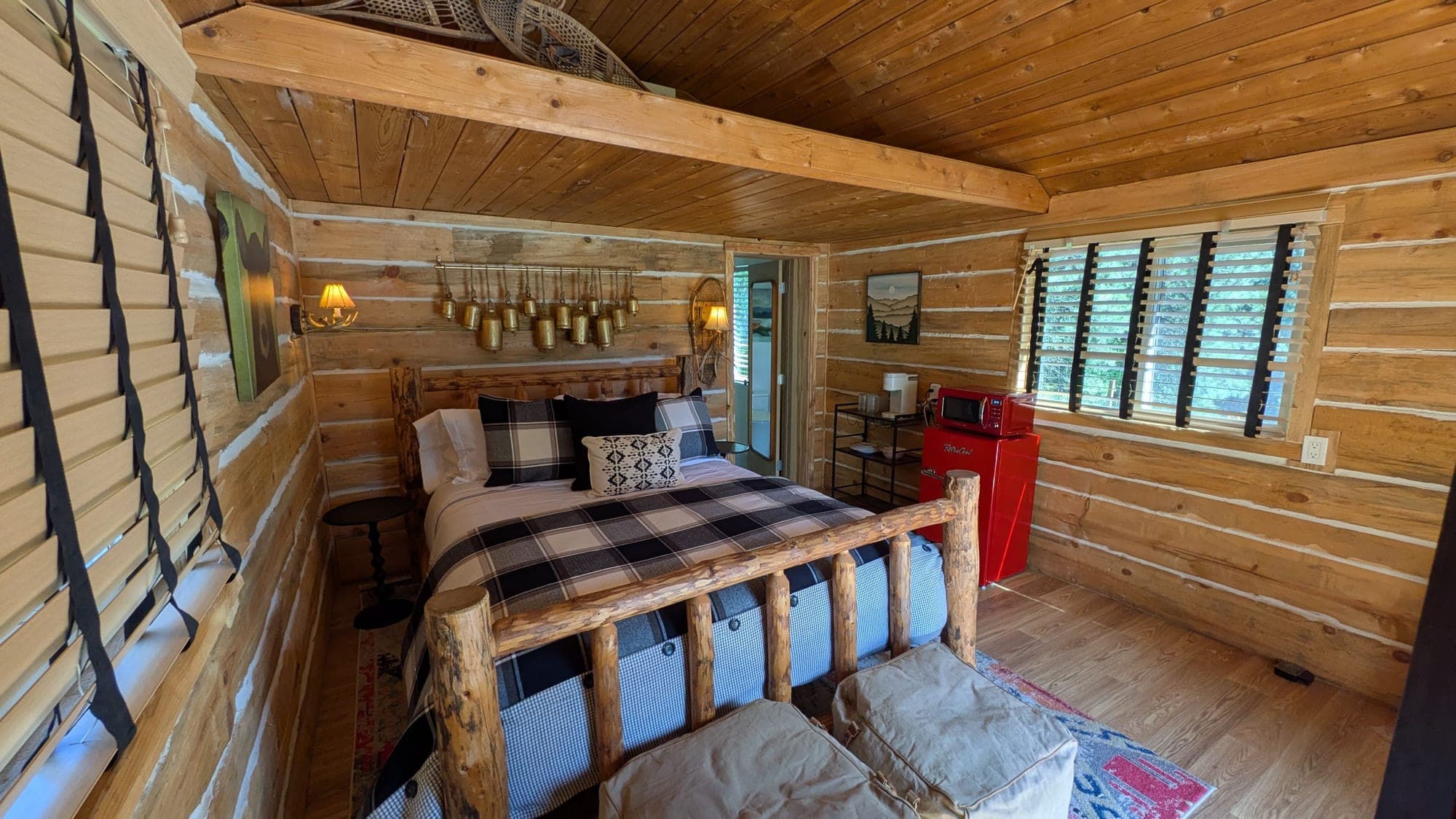 Warm lamp light over the cowbell-headboard bed inside Pop's Log Cabin at Watson's Lakefront Resort