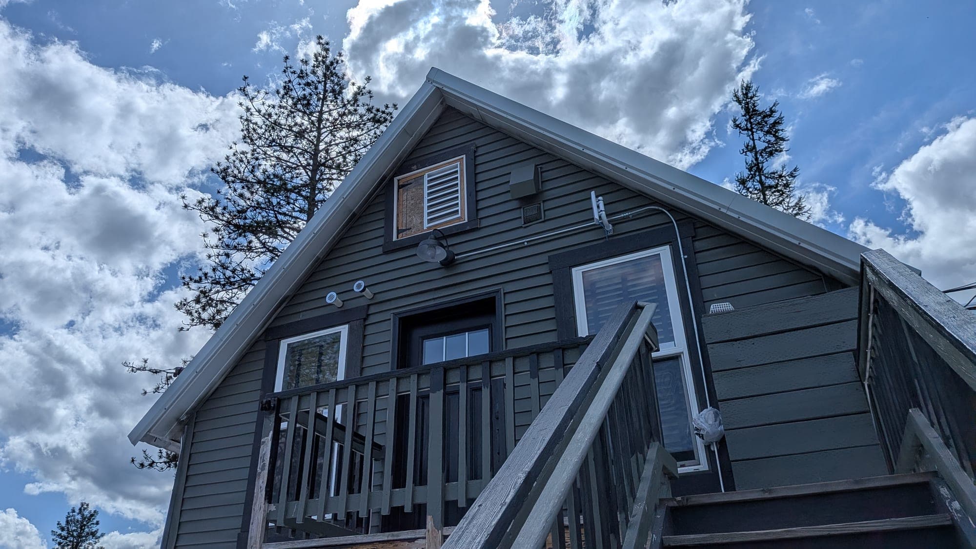 The Tavern Lodge exterior with green-painted siding, peaked roof, and the wooden stairs leading up to the unit above Red's Tavern