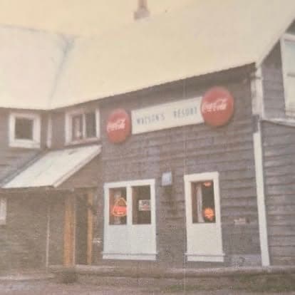 Vintage photograph of the original Watson's Resort storefront with mounted Coca-Cola signs above the door